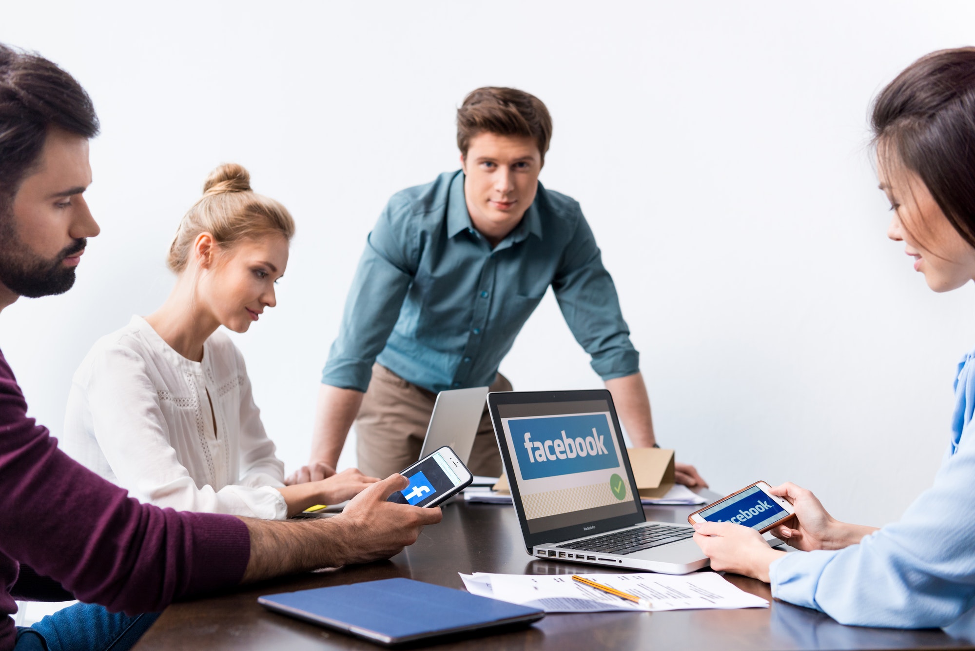 young-businesspeople-using-digital-devices-with-facebook-logo-icons-on-screens.jpg
